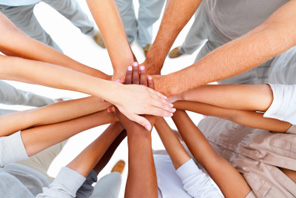 bovenaanzicht van het midden van een cirkel mensen, die hun handen op elkaar leggen als symbool van samenwerking