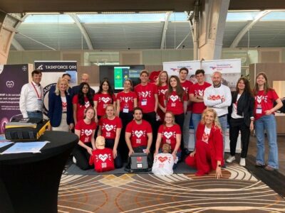 een groepsfoto van vertegenwoordigers van Taskforce QRS en Keep the Heartbeat Going, allen gekleed met rode T-shirts met een hart erop